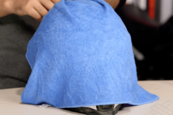 Uma toalha morna e molhada colocada sobre um capacete para amolecer a sujeira