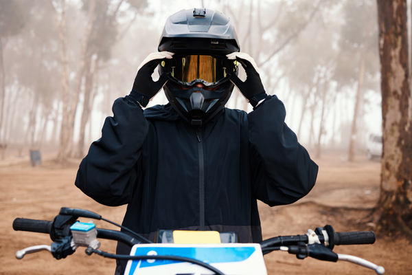 Homem em sua moto na floresta usando capacete trail e óculos refletivo