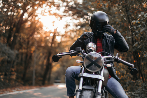 motociclista em sua moto usando uma jaqueta preta e um capacete fechado