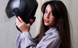 uma mulher jovem de cabelo preto provando um dos Capacetes Mais Procurados por Motociclistas